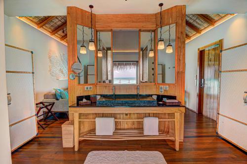 a bathroom with a vanity with a large mirror at Constance Moofushi Maldives - All Inclusive in Himandhoo 