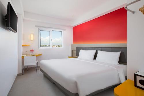 a bedroom with a white bed and a red wall at Amaris Hotel Malioboro - Jogja in Yogyakarta