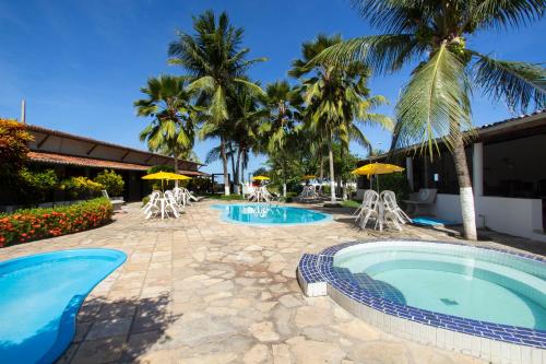 a resort with two pools and chairs and palm trees at Pousada Do Inglês in Jacumã