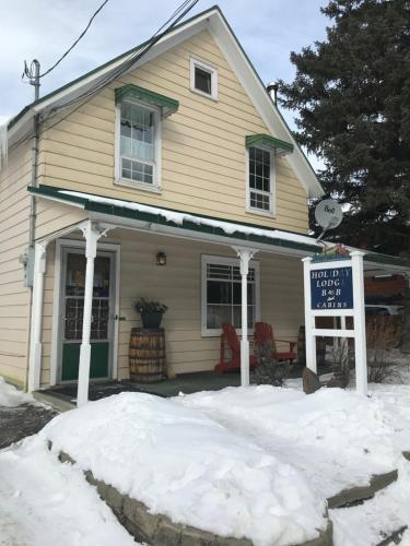 a house with a sign in the snow at Holiday Lodge Bed and Breakfast in Banff