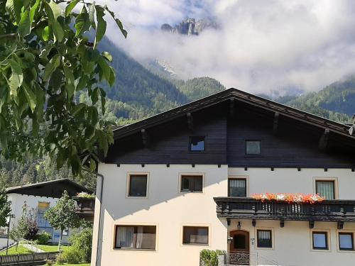 a white house with a black roof with mountains in the background at Simiterhof Lavant in Lavant