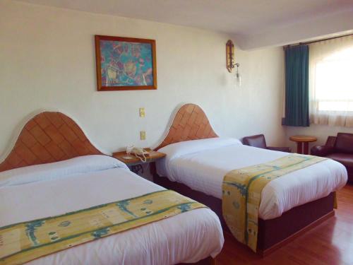 a hotel room with two beds and a couch at Hotel La Posada in Apizaco