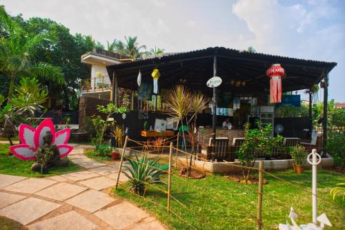 a house with a pink flower in the yard at Lotus Sutra Beachfront Resort in Arambol