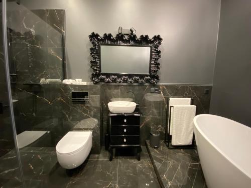 a bathroom with a toilet and a sink and a tub at Gray Apartment in Wrocław