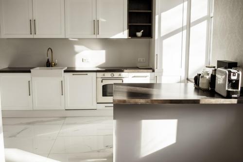 cocina con armarios blancos y encimera en Concert Hall boutique apartment, en Cēsis