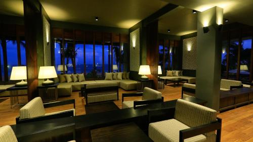 a living room with couches and tables and windows at Pandanus Beach Resort & Spa in Bentota