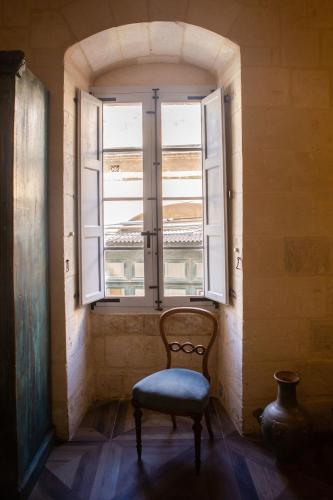 a chair sitting in front of a window at Palazzino Birgu Host Family Bed and Breakfast in Vittoriosa
