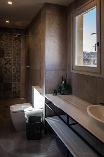 a bathroom with a toilet and a sink and a window at Palazzino Birgu Host Family Bed and Breakfast in Vittoriosa