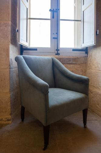 a blue chair sitting in a room with windows at Palazzino Birgu Host Family Bed and Breakfast in Vittoriosa