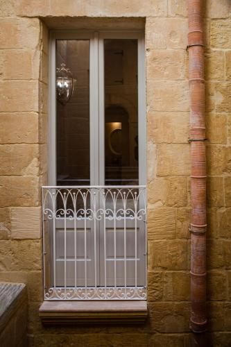 a window with a white railing on a building at Palazzino Birgu Host Family Bed and Breakfast in Vittoriosa