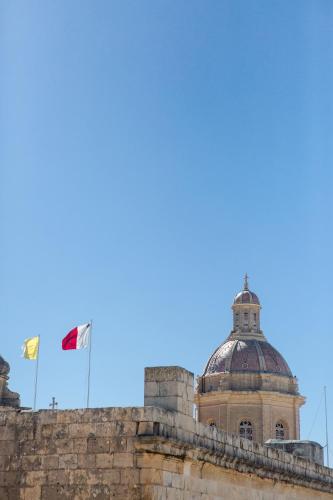 a building with two flags on top of it at Palazzino Birgu Host Family Bed and Breakfast in Vittoriosa