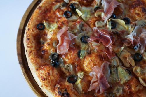 a pizza with ham and olives on a plate at La Bella Boutique Hotel in Tagaytay