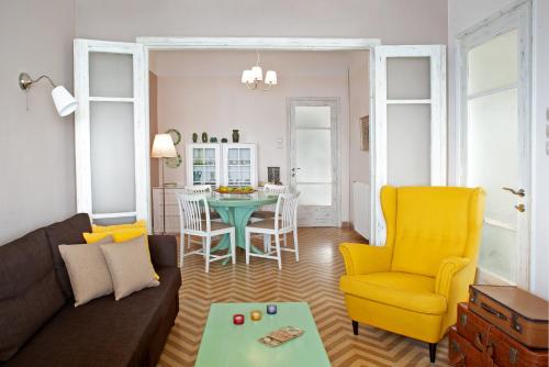 a living room with a couch and a table and yellow chairs at Avgi by the Sea in Kala Nera