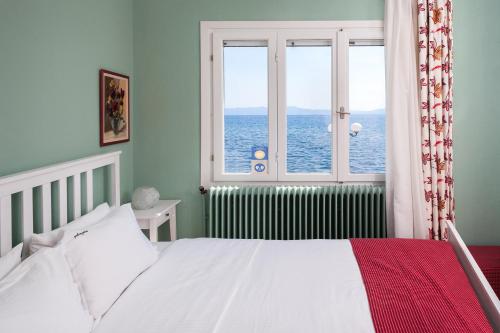 a bedroom with a bed and a window with the ocean at Avgi by the Sea in Kala Nera
