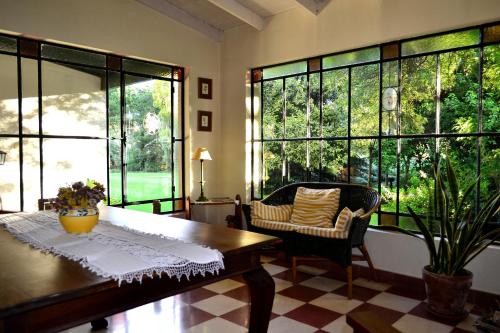 un soggiorno con tavolo, sedie e ampie finestre di Casa de Campo Las Acacias a Tandil