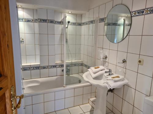 ein Badezimmer mit einem Waschbecken, einer Badewanne und einem Spiegel in der Unterkunft Hotel Seelust in Hohwacht