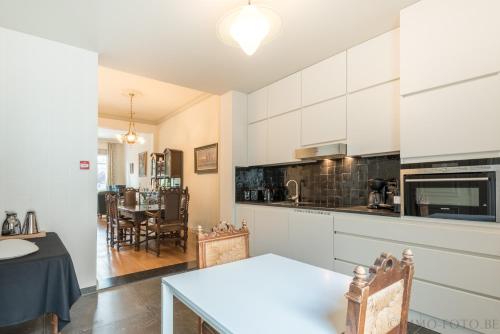 a kitchen with white cabinets and a dining room at Dendernachten in Dendermonde