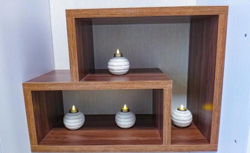 four white vases are sitting in a wooden shelf at Комфортная студия на Южном вокзале in Kharkiv