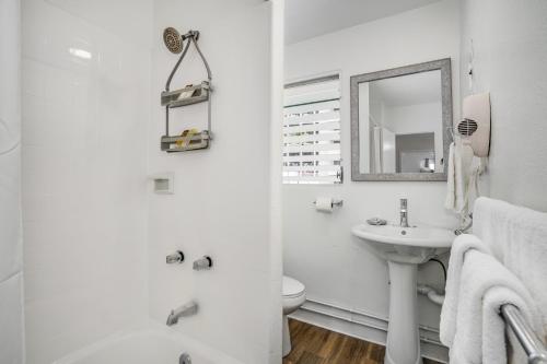 a white bathroom with a sink and a mirror at Aloha Suites Waikiki in Honolulu