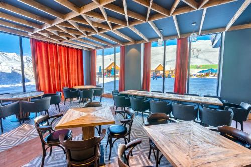 un restaurant avec des tables et des chaises et de grandes fenêtres dans l'établissement GVC 510 New Gudauri Mountain view, à Goudaouri