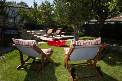 a group of chairs sitting in the grass at Villa Erifili by Pelion Esties in Agios Georgios Nilias