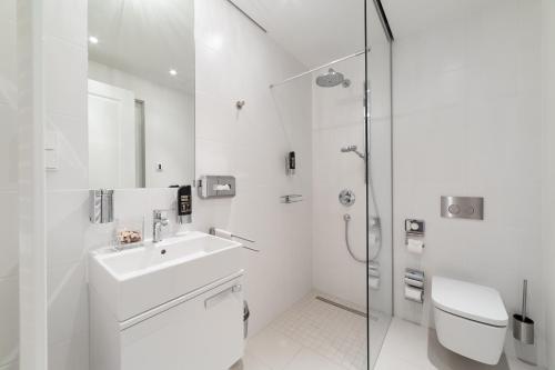 een witte badkamer met een wastafel en een douche bij Modernes Apartment am Neumarkt in Dresden