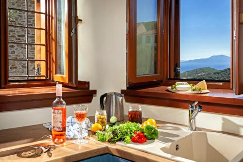 a kitchen with a sink with a bottle of wine and vegetables at Villa Ioanna by Pelion Esties in Áno Gatzéa