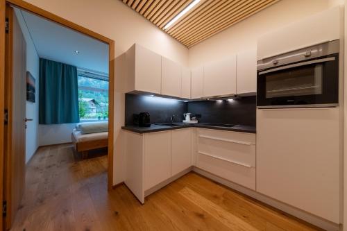 a kitchen with white cabinets and a large window at Känzele Appartements in Reuthe