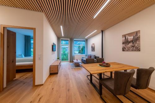 a dining room and living room with a wooden ceiling at Känzele Appartements in Reuthe