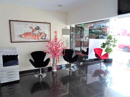 a room with chairs and a vase with pink flowers at SENG WAH HOTEL in Singapore
