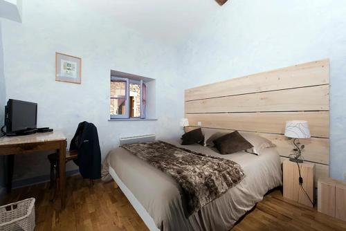 een slaapkamer met een bed, een bureau en een televisie bij GITE DU ROY D'AMONT (Plaine de l'Ain) in Lagnieu