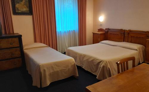 um quarto de hotel com duas camas e uma janela em Hotel Tortorina em Urbino