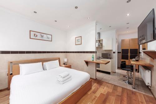 Argyle Apart Hotel في لندن: غرفة نوم بسرير ابيض كبير ومطبخ