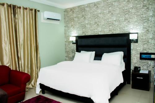 a bedroom with a white bed and a red couch at Shamrockmanor(TheResidence) in Benin City
