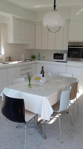 a white kitchen with a table with chairs and a bottle of wine at Vakantiehuis Bloemmolenkaai in Diksmuide