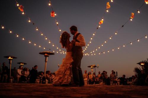 a bride and groom dancing in front of lights at Villa Santa Cruz in Todos Santos