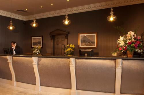 a woman standing at a bar in a room with flowers at Clanree Hotel & Leisure Centre in Letterkenny
