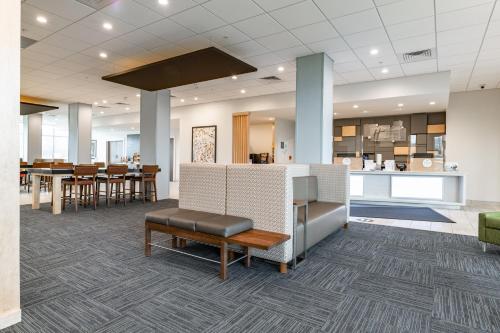 a lobby with tables and chairs and a kitchen at Holiday Inn Express & Suites - Moundsville by IHG in Moundsville