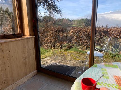 a room with a window with a table and a view at Gîte " Orée des bois" in Vertolaye