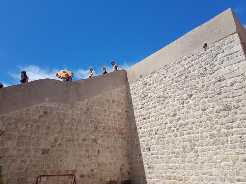 Un gruppo di persone che si trovano sopra un muro di mattoni di Apartments Abjanic a Dubrovnik