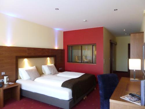 a bedroom with a large bed with a red wall at Hotel Salzburg in Salzburg