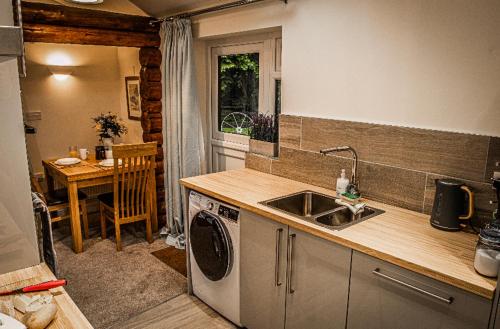 uma cozinha com um lavatório e uma máquina de lavar roupa em Log cabin em Coventry