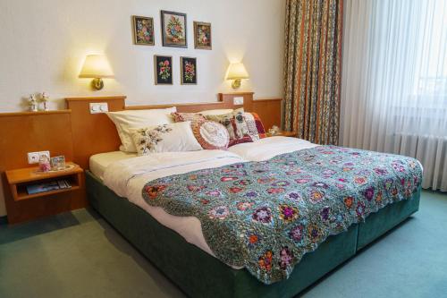 Un dormitorio con una cama con una colcha colorida. en Tante ALMA's Kölner Hotel en Colonia