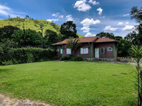 una casa con un césped verde delante de ella en Pousada das Pedras, en Passa Quatro