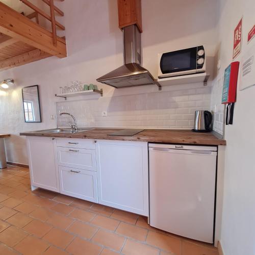 a kitchen with white cabinets and a sink at Alba Odeceixe - casa alta in Odeceixe