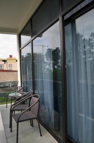 two chairs and tables on a balcony with windows at White Hotel in K'obulet'i