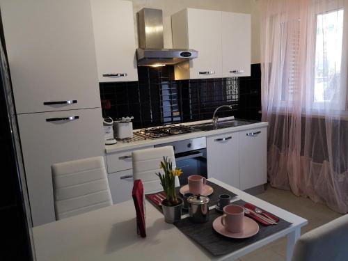 a kitchen with white cabinets and a table with dishes on it at La CasAffittiera Apartments Group in Anzio