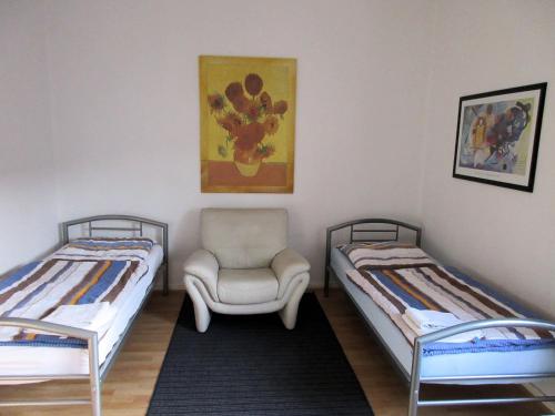ein Zimmer mit 2 Betten und einem Stuhl darin in der Unterkunft Studio Apartment - Messe Nord in Hannover