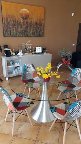 una mesa de cristal con sillas y una mesa con flores. en Il Faggio 17 B&B, en Artena