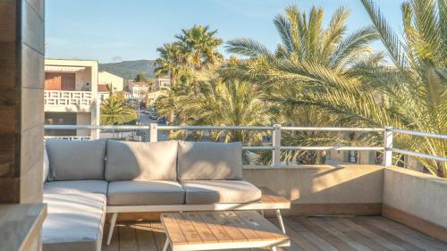 un sofá sentado en un balcón con palmeras en La Palmeraie Galli - Duplex de Charme, en Sanary-sur-Mer